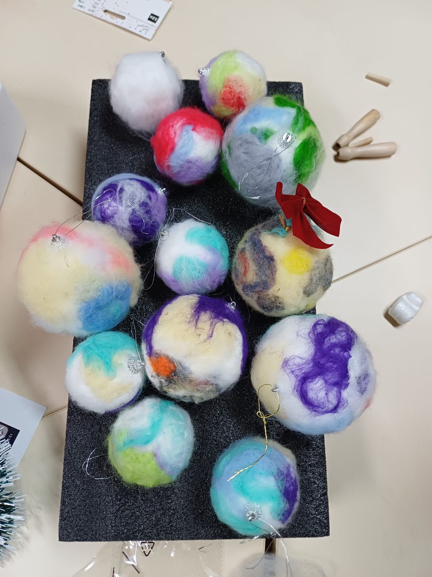 Na stolu su raspoređene gotove božićne jelke od kartona i kuglice od vune koje su izradili korisnici.