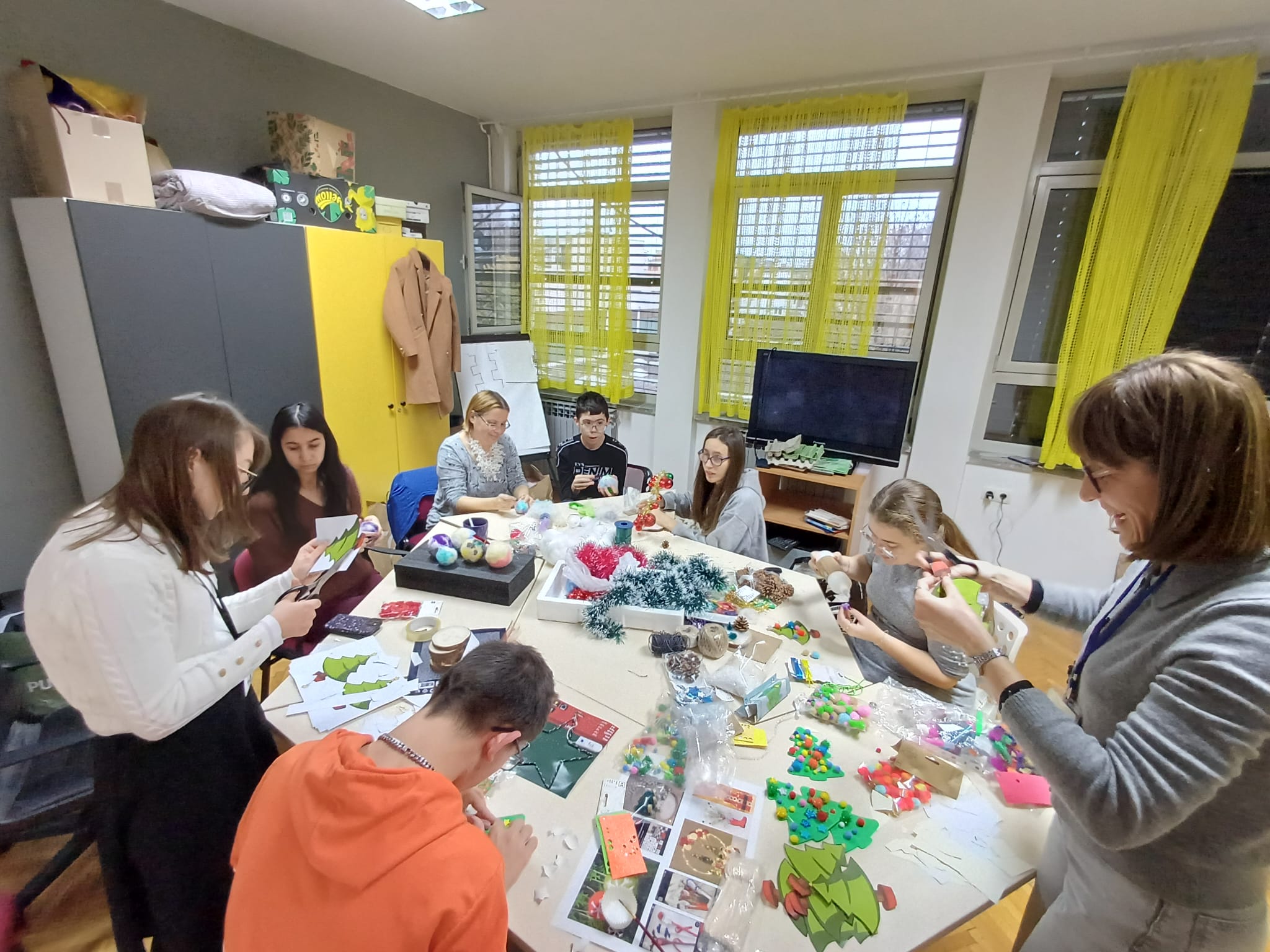 Panoramski prikaz učionice prikazuje više korisnika koji za stolovima izrađuju božićne ukrase.