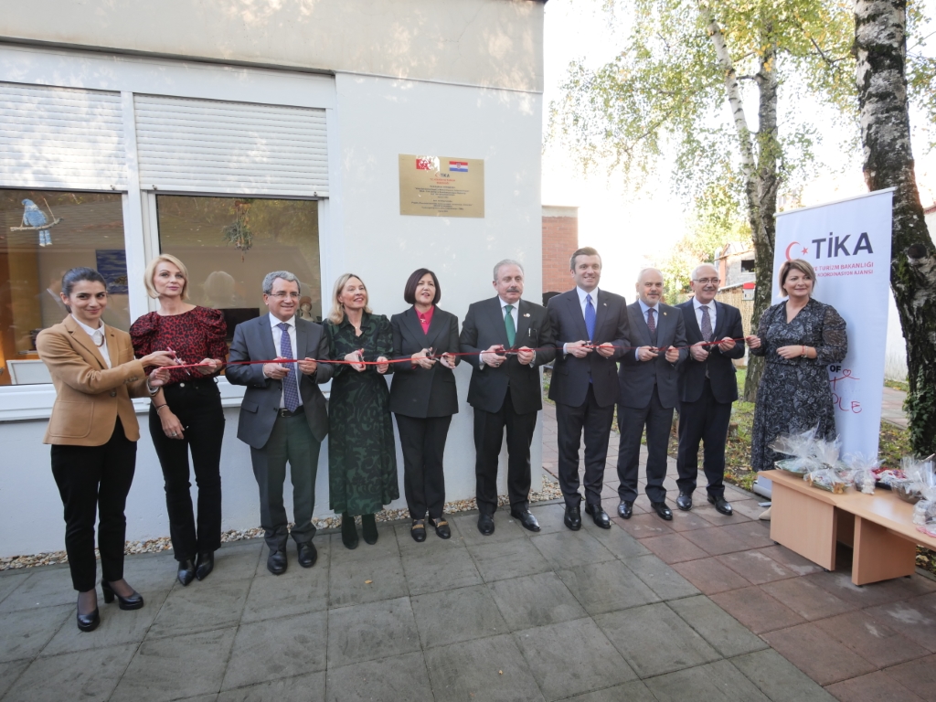 Grupna fotografija članova svečanog posjeta. Na slici se nalazi 10 ljudi koji ceremonijalno drže svečanu vrpcu te je režu kao znak službenog otvorenja projekata